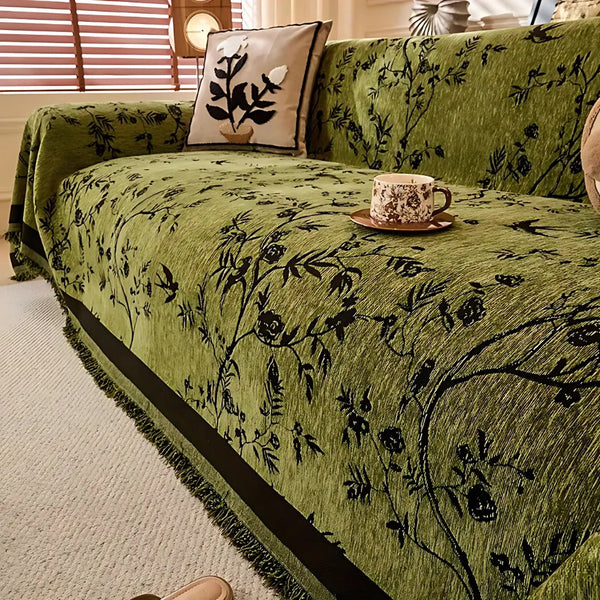 Floral jacquard chenille sofa throw in olive green draped over a modern couch with tassel fringe detail