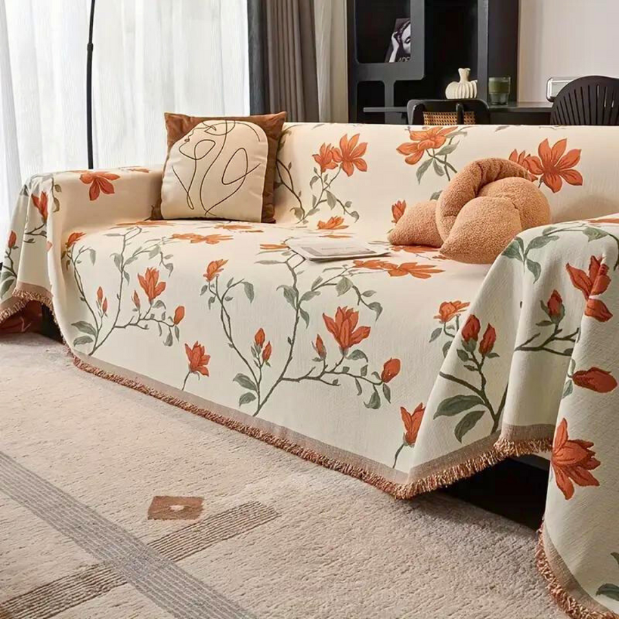 Vintage floral chenille sofa cover in beige orange draped across a living room couch with tassel trim detail