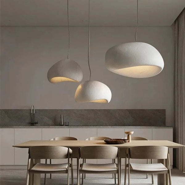 Wabi-sabi pendant light with organic textured shade hanging above a dining table in a warm-toned interior