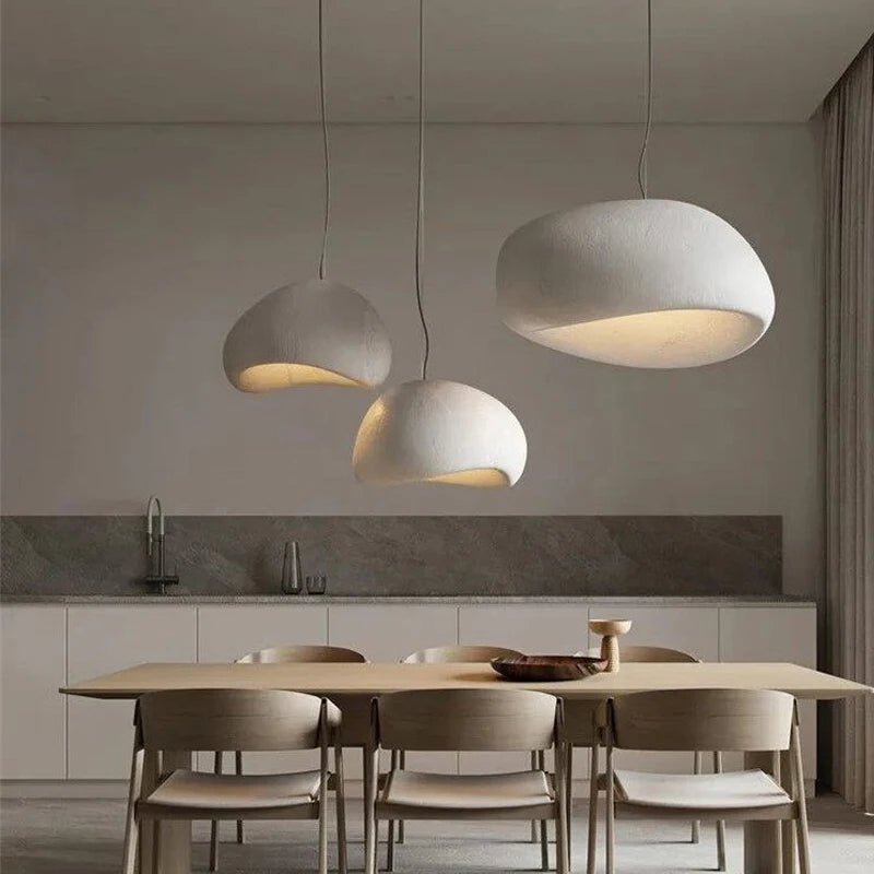 Wabi-sabi pendant light with organic textured shade hanging above a dining table in a warm-toned interior