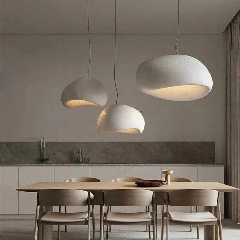 Wabi-sabi pendant light with organic textured shade hanging above a dining table in a warm-toned interior