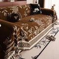 Woodland Charm sofa cover casually draped over an armchair beside a wooden side table with dried foliage
