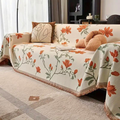 Vintage floral chenille sofa cover in beige orange draped across a living room couch with tassel trim detail