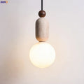 Detail shot of the natural travertine veining patterns on the pendant light body in warm daylight