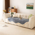 Olive green chenille tassel sofa cover styled on a modern sofa with earthy throw pillows and natural decor