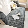 Detail shot of hand-pleated edge finishing on the plush flannel sofa cover in a warm interior setting
