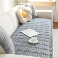 Lifestyle image of plush sofa cover in Snow Drift on a sectional with a cozy blanket and candle nearby